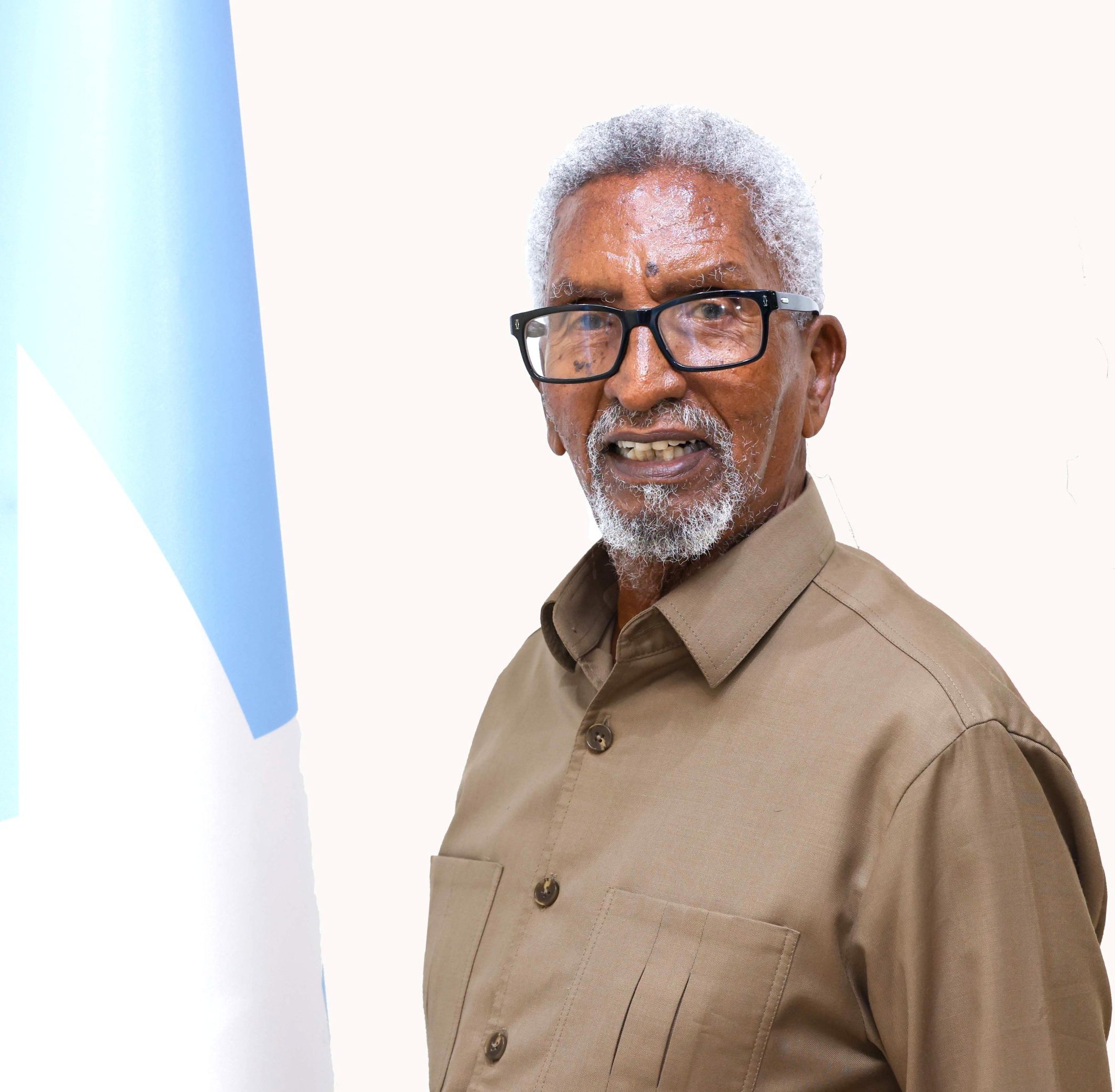 Man with white hair and glasses wearing light shirt